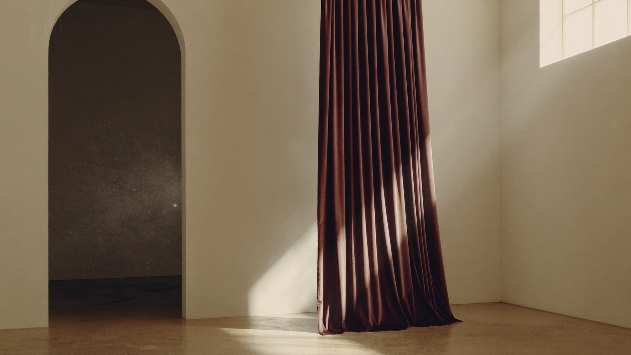 A quiet gallery interior with aubergine velvet drapery in soft light.